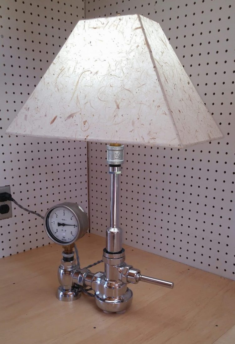 The lamp was made using a Sloan Plumbing Royal Flushometer. In 1906 W.E. Sloan invented the Royal Flushometer which released a measured amount of water to flush bathroom devices. While sales were slow; one in 1906, two in 1907,then 150 in 1908; the original design has proved to be so reliable that the same design is used today. In this lamp the flush bar is now the switch.